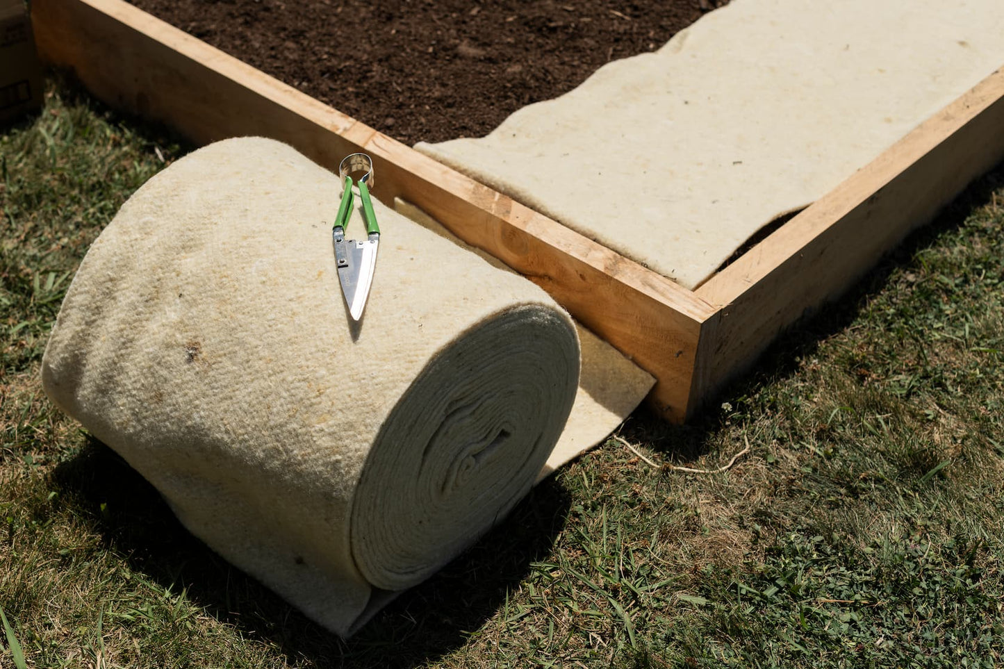 Wool mulch mat rolls rolled out and ready for installation in garden